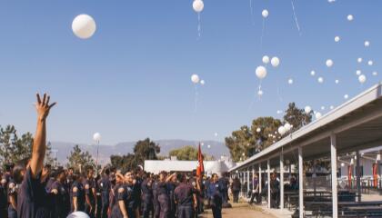 Students watching white balloons floating in the air